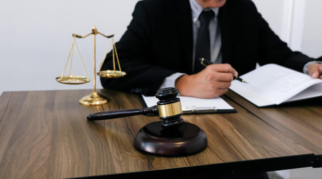 Lawyer is sitting on the table with gavel and writing 