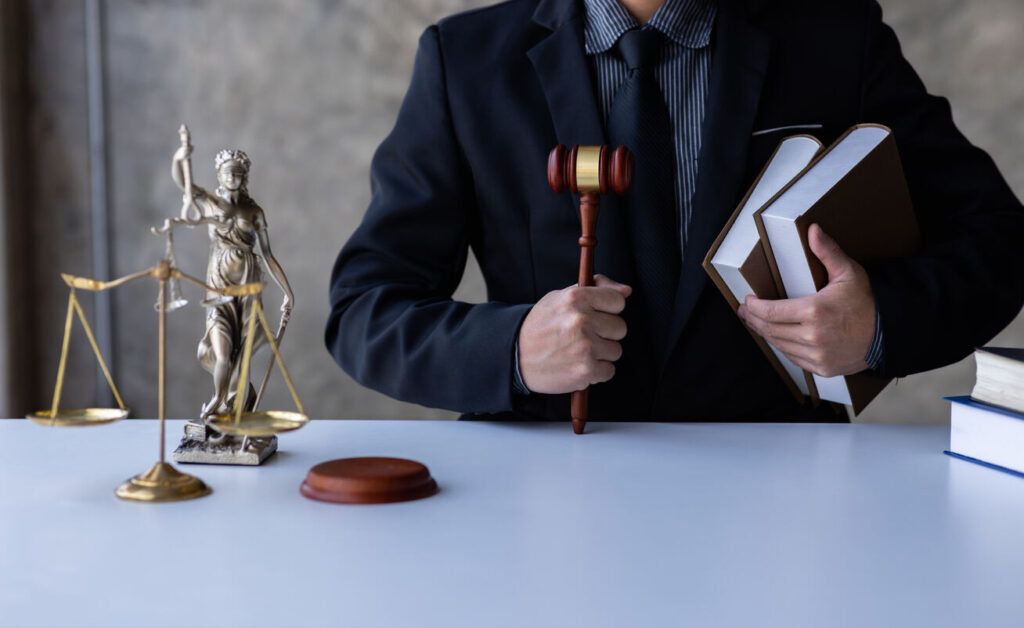 Lawyer is sitting on the table with holdinglaw books and gavel.