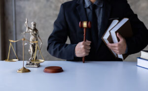 Lawyer is sitting on the table with holdinglaw books and gavel.