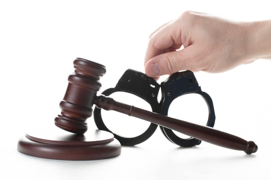 Hand placing handcuffs next to a gavel symbolizing criminal defense